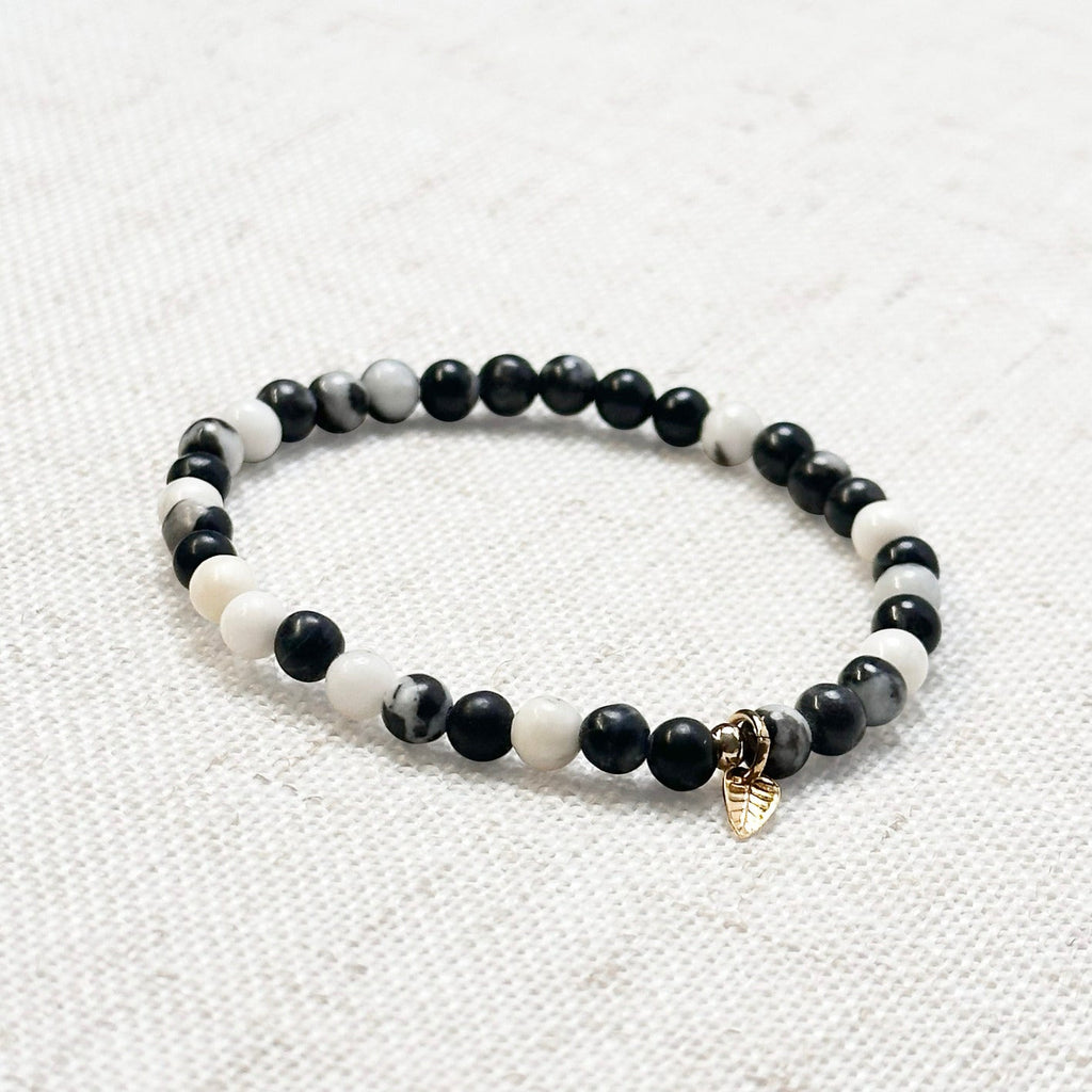 4mm zebra jasper bracelet with golden leaf charm displayed on soft fabric