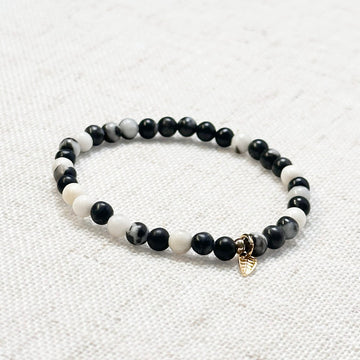 4mm zebra jasper bracelet with golden leaf charm displayed on soft fabric