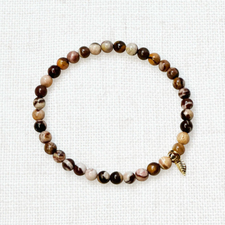 Elegant Australian zebra jasper bracelet with golden charm in sunlight