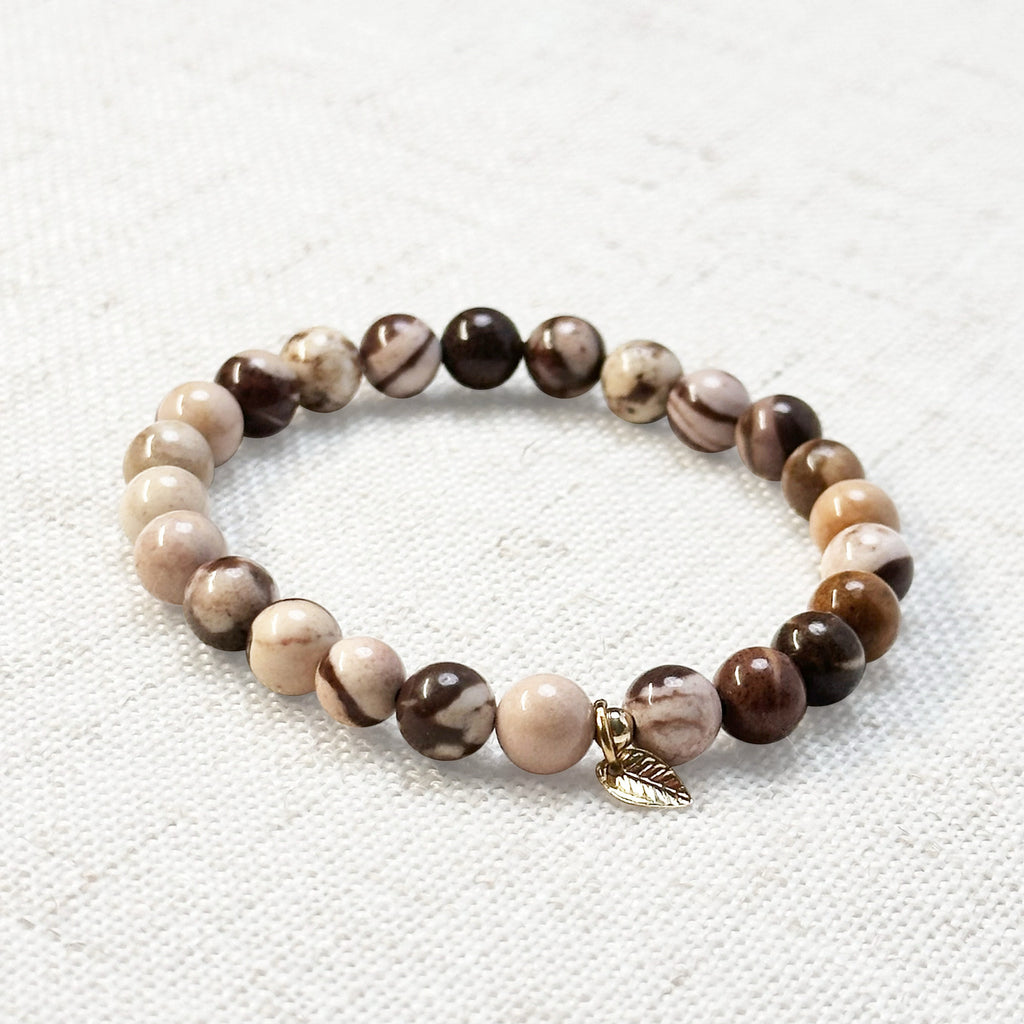 6mm zebra jasper bracelet with golden leaf charm on neutral background