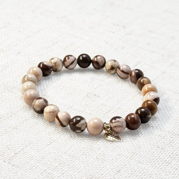 6mm zebra jasper bracelet with golden leaf charm on neutral background