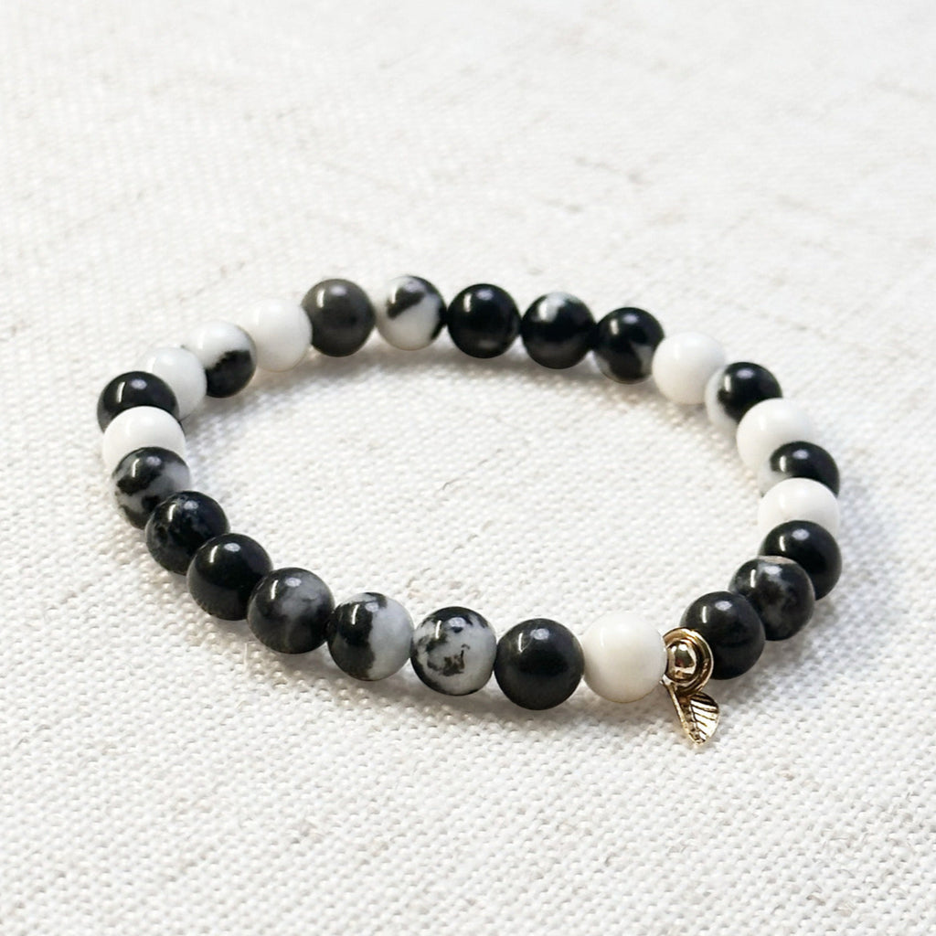 6mm zebra jasper bracelet with golden leaf charm displayed on linen
