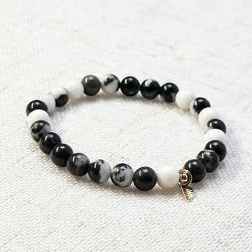 6mm zebra jasper bracelet with golden leaf charm displayed on linen