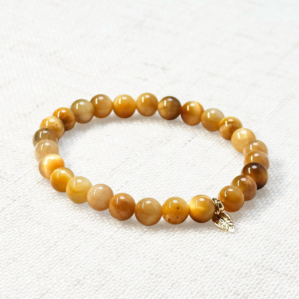 Golden Tiger’s eye bracelet 6mm with golden leaf charm on neutral background