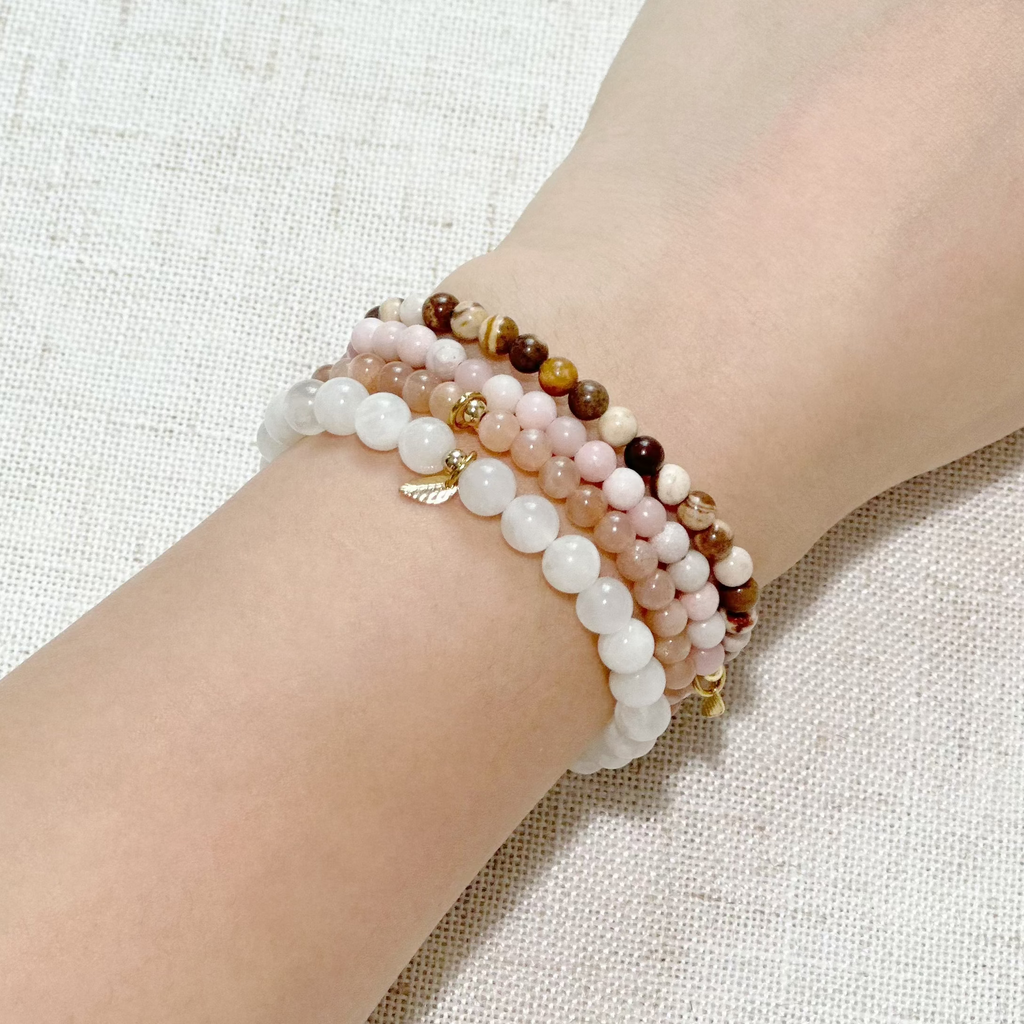 Close-up of healing crystal bracelets featuring warm pinks, creams, and grounding earth tones.