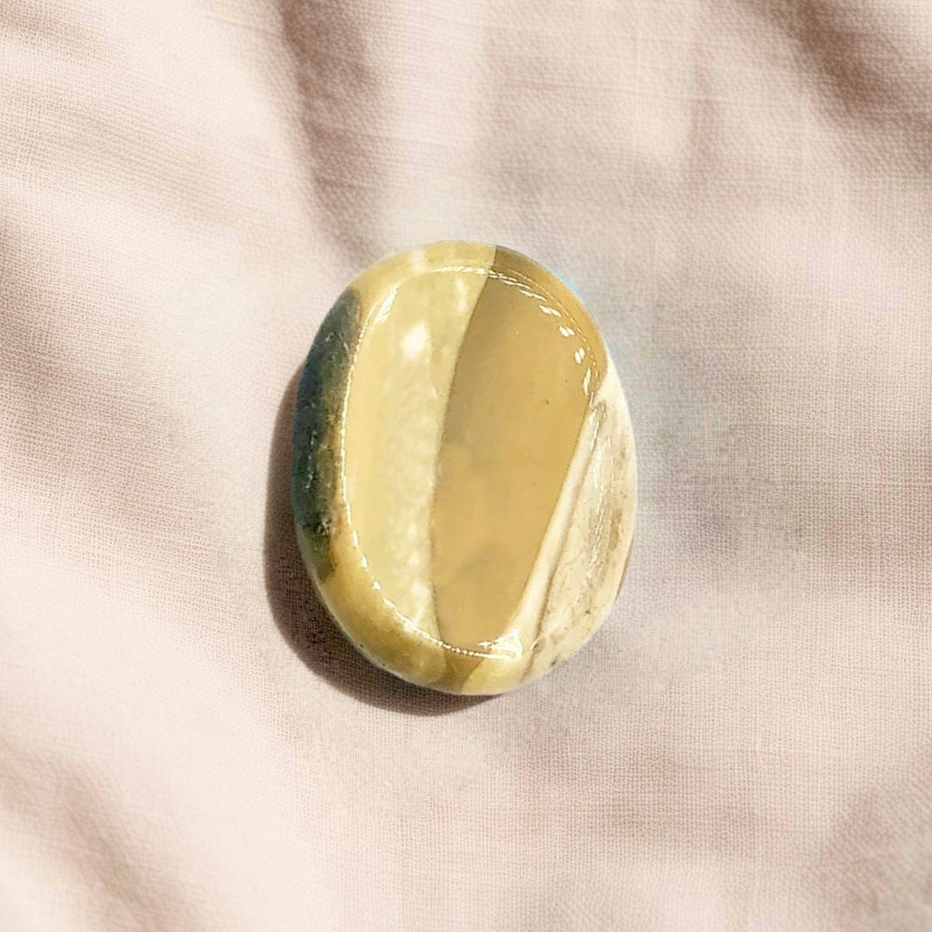 Polished Mookaite Jasper crystal worry stone in a thumb shape, promoting strength, focus, and stability.