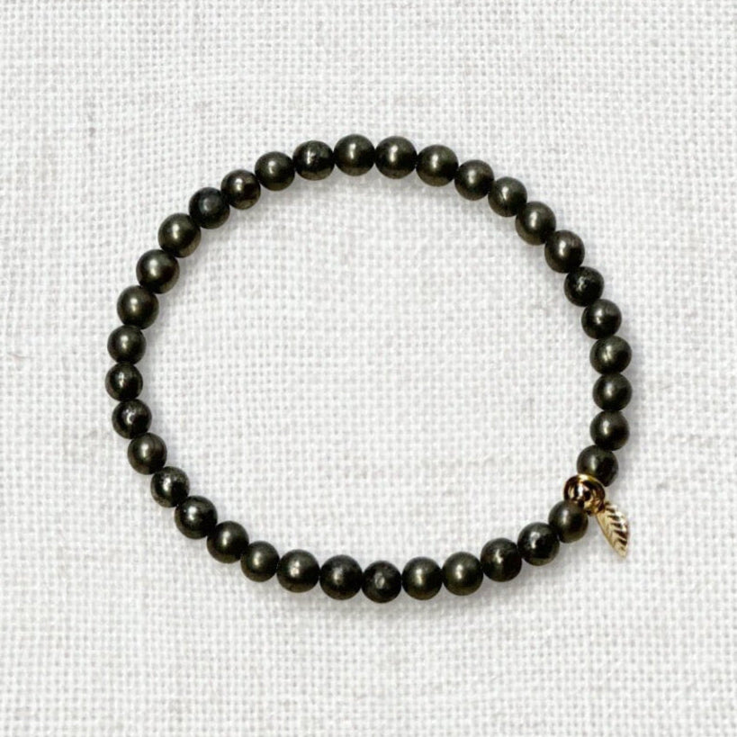 Natural pyrite energy bracelet on neutral background with elegant gold charm