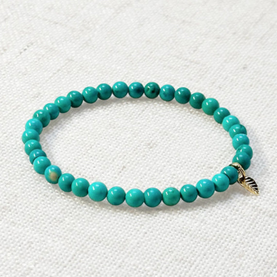 Turquoise bracelet with 4mm beads and golden leaf charm on neutral background