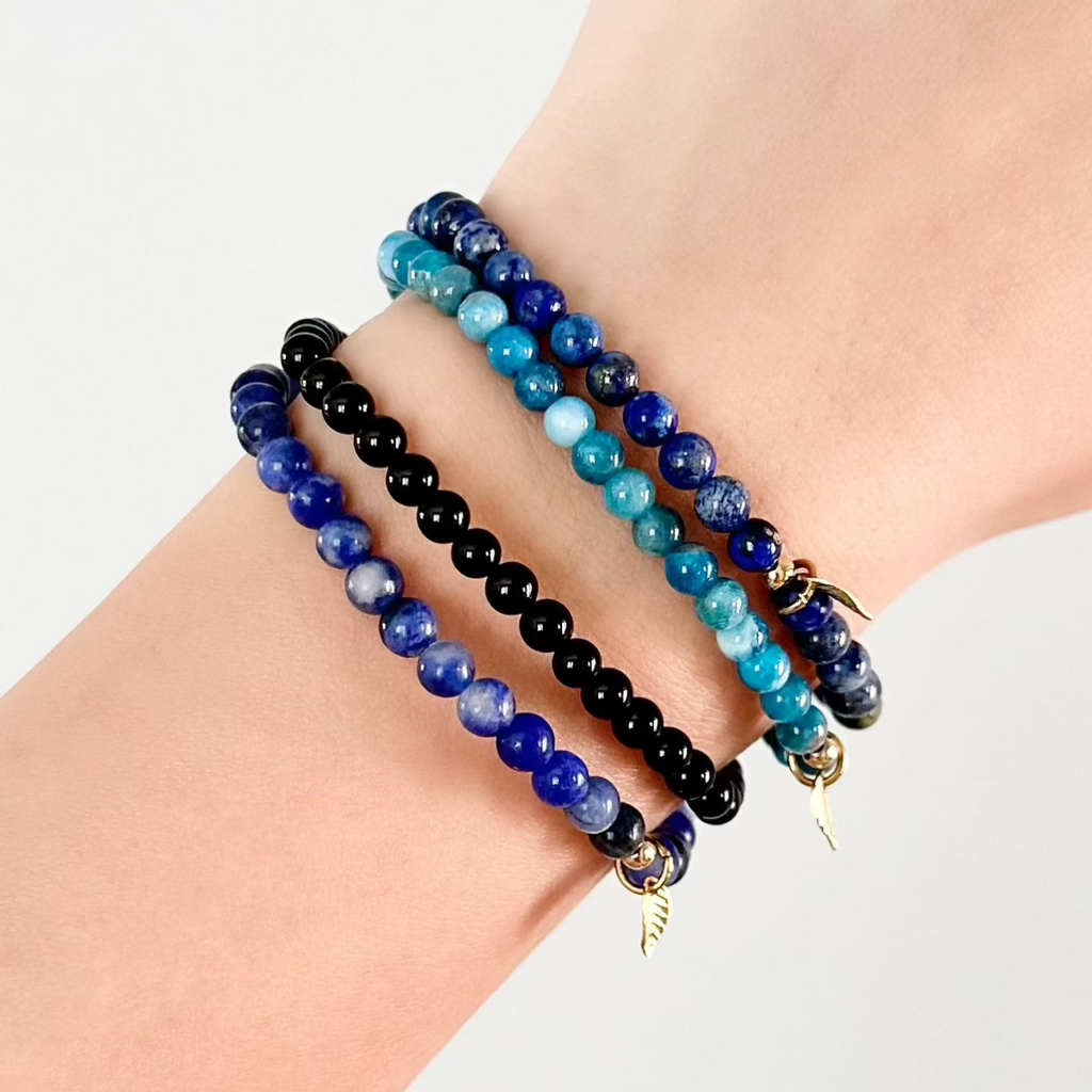 Stacked Virgo crystal bracelets with earthy blue and black tones