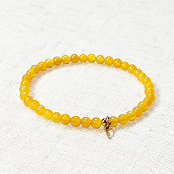 Yellow carneol bracelet with 4mm beads and golden leaf charm on natural fabric