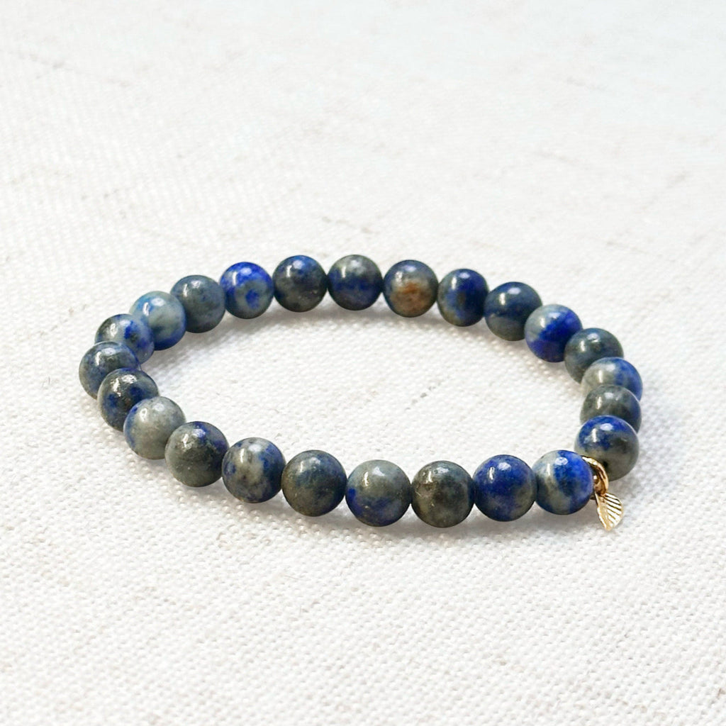 Deep blue lapis lazuli bracelet with golden leaf charm for wisdom and clarity
